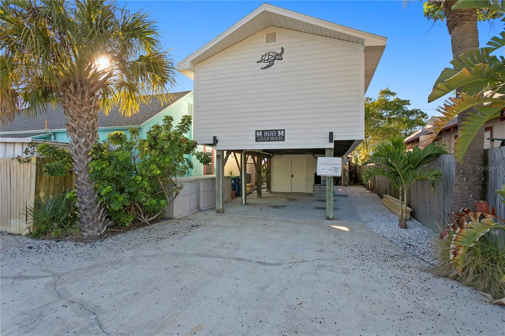An elevated house with white siding stands on wooden pilings above a concrete driveway — 800 GULF BOULEVARD UNIT 5, INDIAN ROCKS BEACH, FL