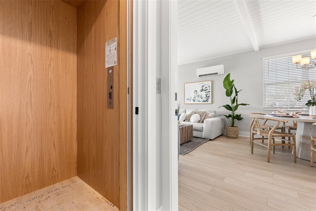 An elevator with wood-paneled walls opens into a bright living and dining area — 4333 SALTWATER PEARL WAY, CORTEZ, FL
