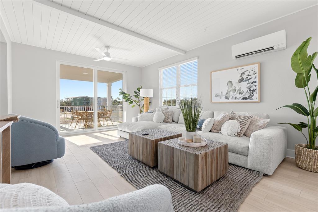 A bright living room features a large sectional sofa, two wooden coffee tables, and sliding doors — 4333 SALTWATER PEARL WAY, CORTEZ, FL