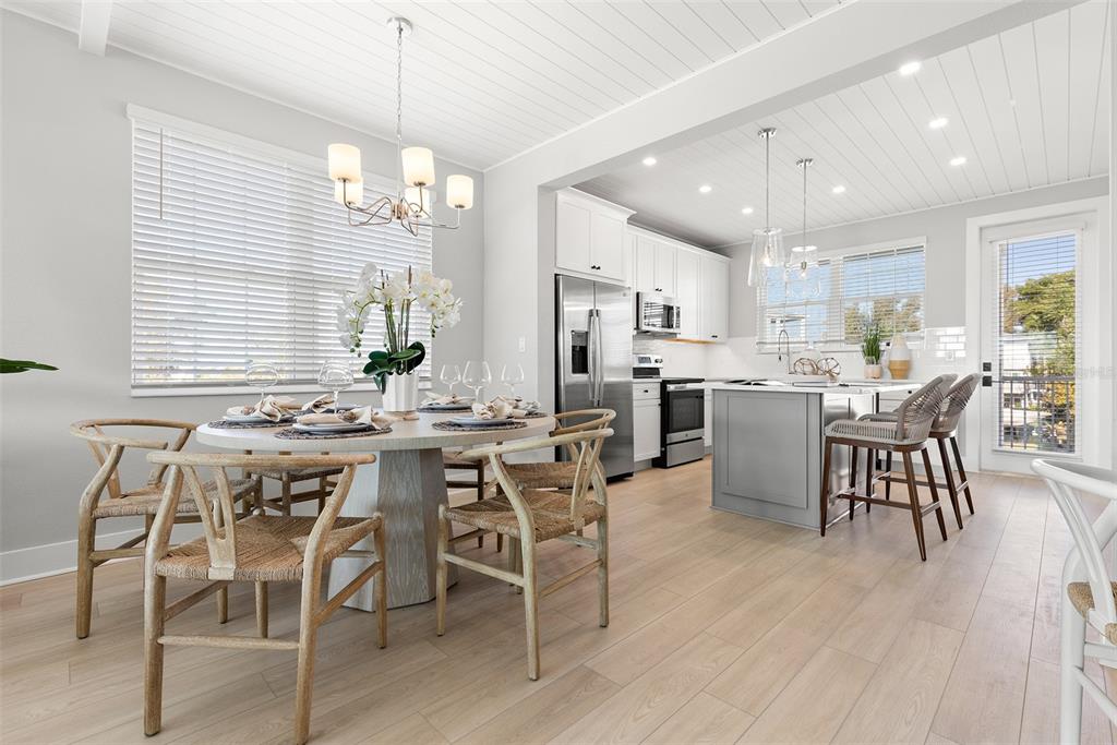 A dining area with a round table and chairs opens into a modern white kitchen — 4333 SALTWATER PEARL WAY, CORTEZ, FL