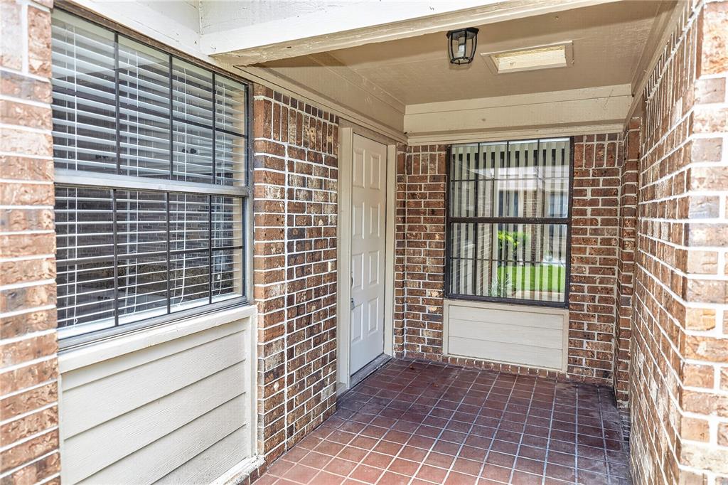 A covered brick porch features a white front door, tiled flooring, and two windows — 168 BERMUDA PETREL COURT, DAYTONA BEACH, FL