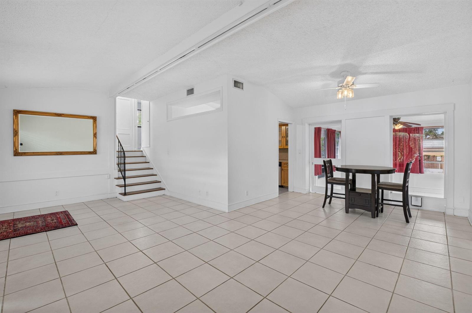 A bright, open-concept room features white walls, tiled flooring, a staircase, and a dining area — 424 NW 12th Avenue, Boca Raton FL 33486, BOCA RATON, FL