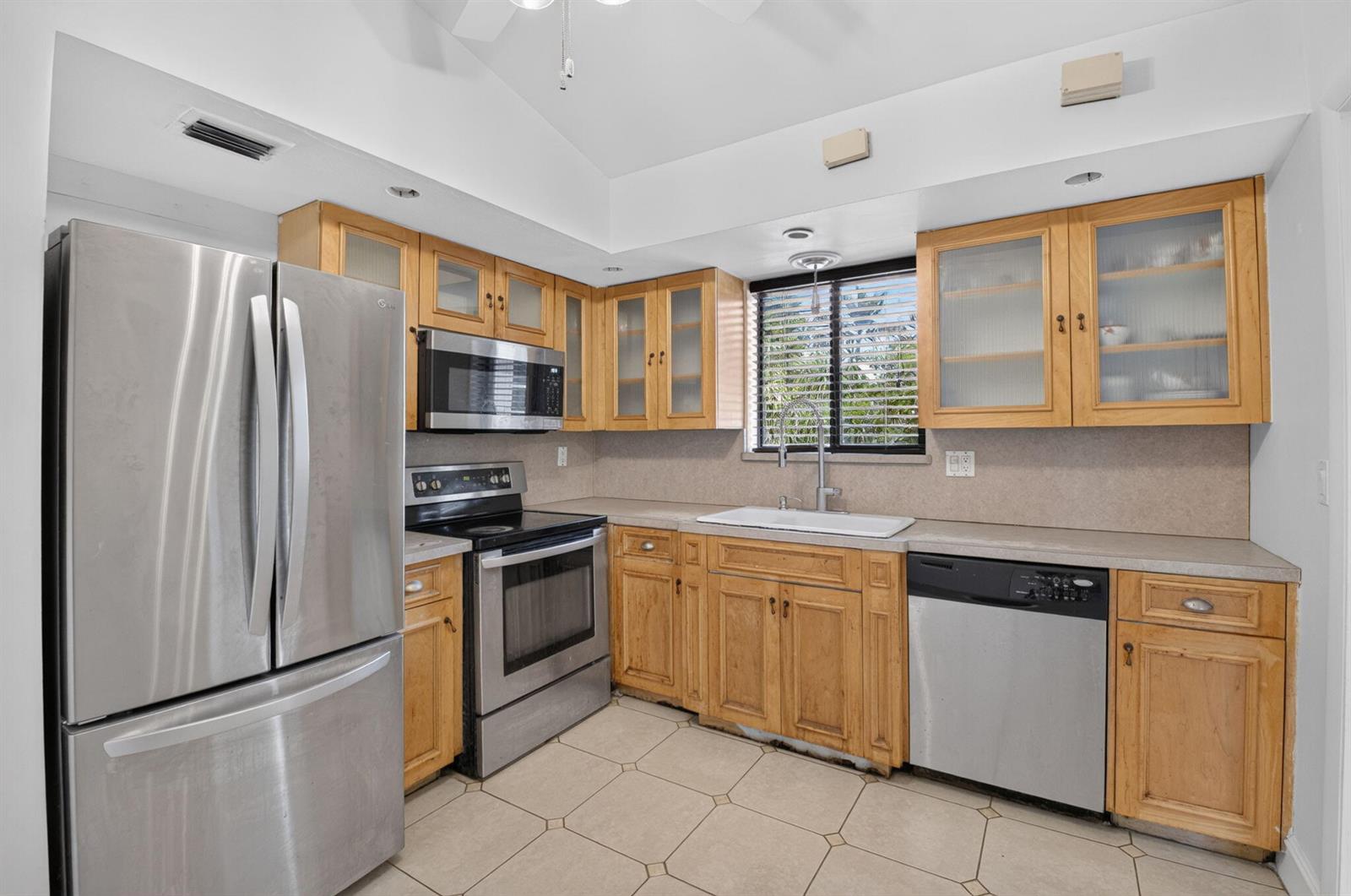 A kitchen features light wood cabinets, stainless steel appliances, a tile floor, and a window — 424 NW 12th Avenue, Boca Raton FL 33486, BOCA RATON, FL