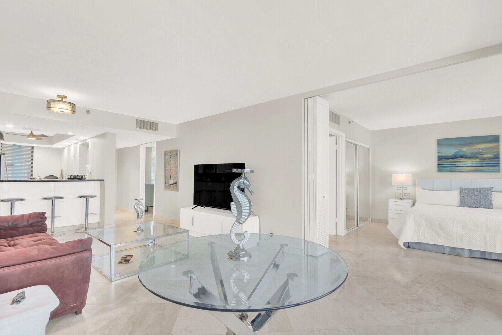 A living room with a glass table and sofa opens into a bedroom with tile floors — 2687 N Ocean Boulevard # 306, Boca Raton FL 33431, BOCA RATON, FL