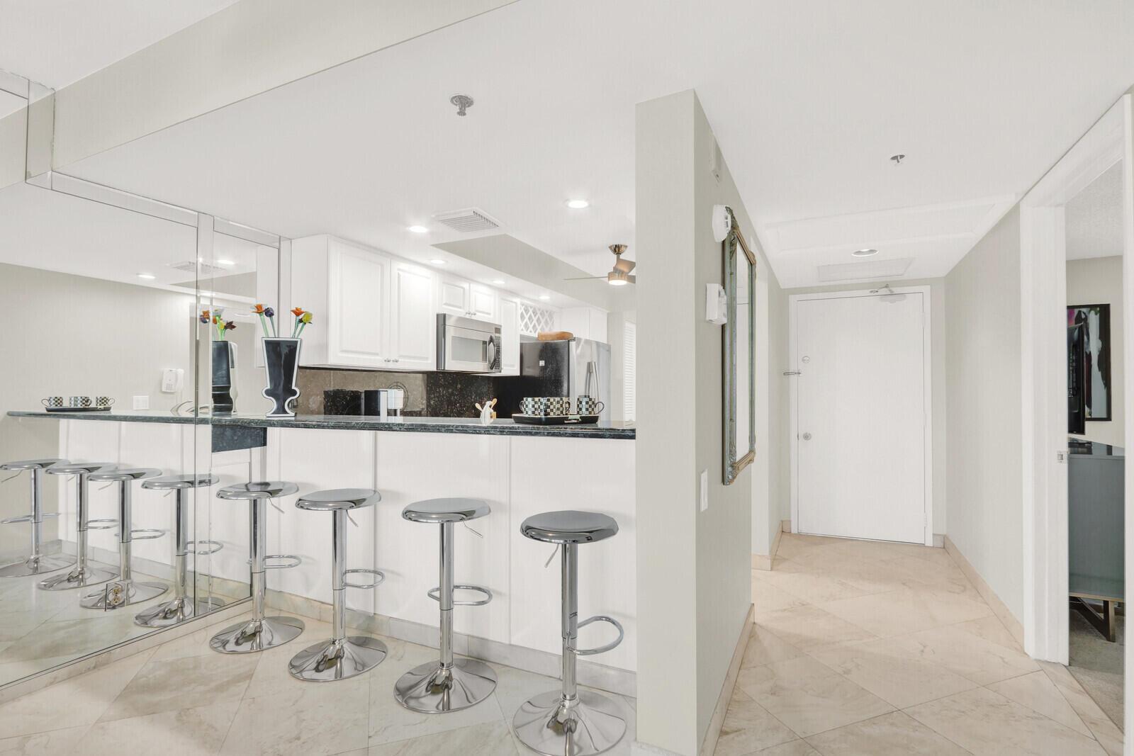 A kitchen with white cabinets and a breakfast bar featuring four chrome stools — 2687 N Ocean Boulevard # 306, Boca Raton FL 33431, BOCA RATON, FL