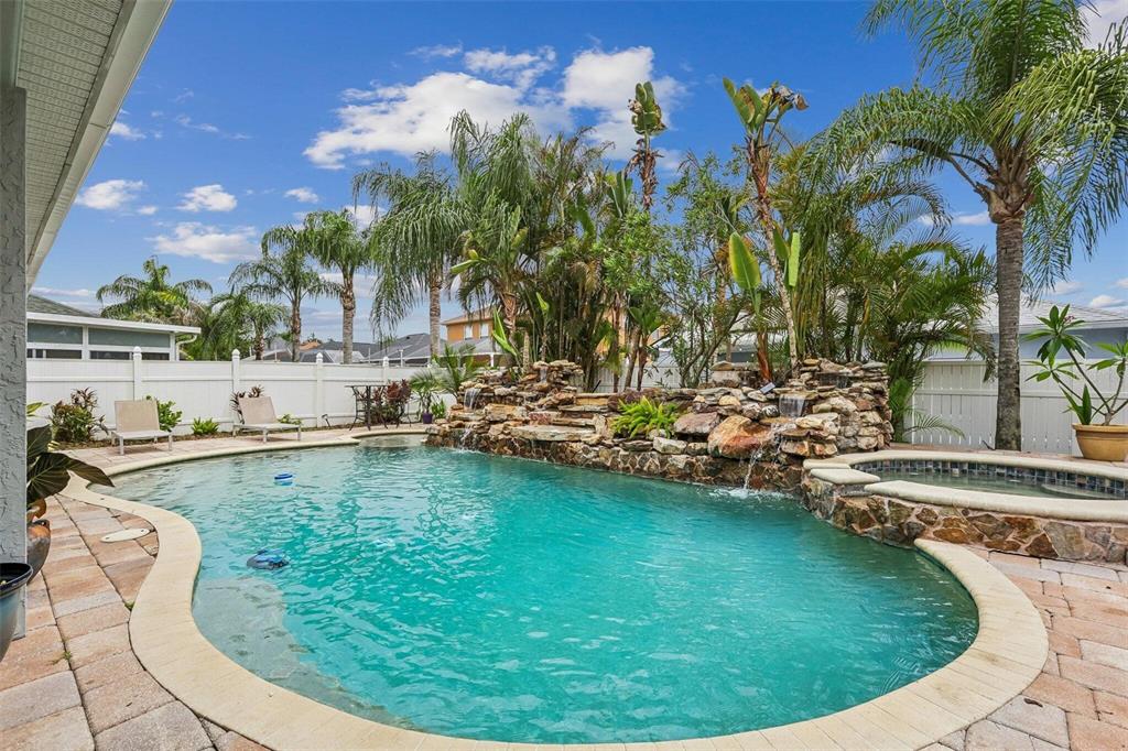 A backyard swimming pool features a rock waterfall, a built-in spa, and surrounding patio pavers — 11612 WINDSORTON WAY, TAMPA, FL