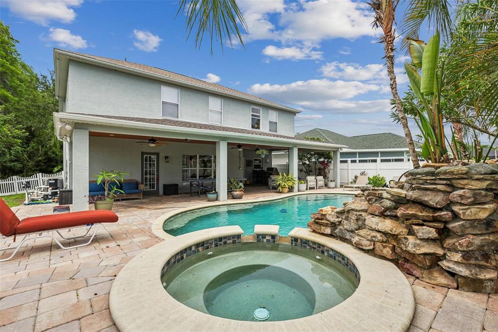 A backyard features a swimming pool, a circular hot tub, and a covered patio area — 11612 WINDSORTON WAY, TAMPA, FL