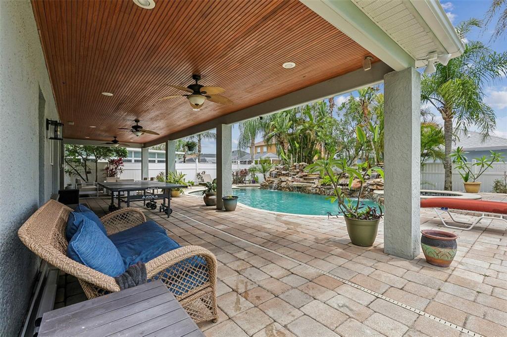 A covered patio features a wood-paneled ceiling, a ping pong table, and a swimming pool — 11612 WINDSORTON WAY, TAMPA, FL
