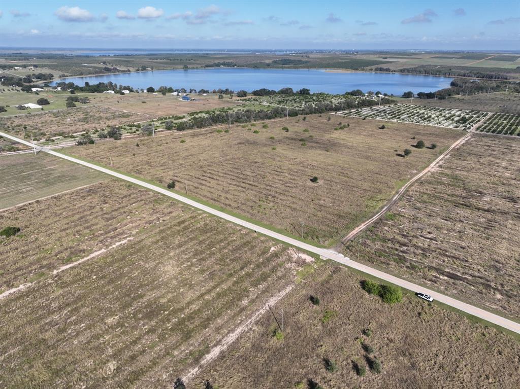 An aerial view shows a large, undeveloped grassy lot bisected by a paved road — 0 MULLINSVILLE ROAD, FROSTPROOF, FL