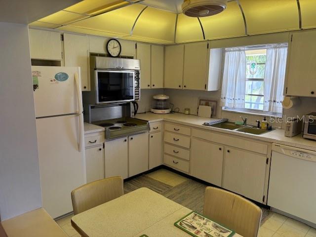 A kitchen features white cabinets, a white refrigerator, a built-in microwave, and a dining table — 4700 COVE CIRCLE UNIT 203, ST PETERSBURG, FL