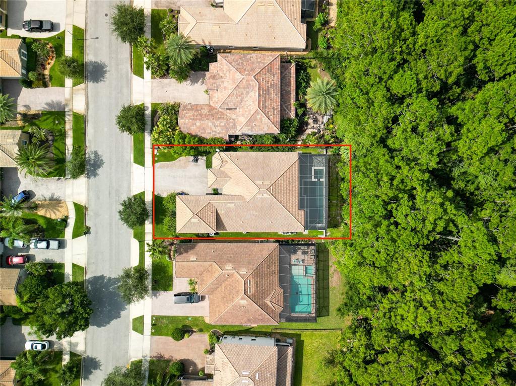 An aerial view shows a single-family home with a screened-in patio and a wooded backyard — 477 LUNA BELLA LANE, NEW SMYRNA BEACH, FL
