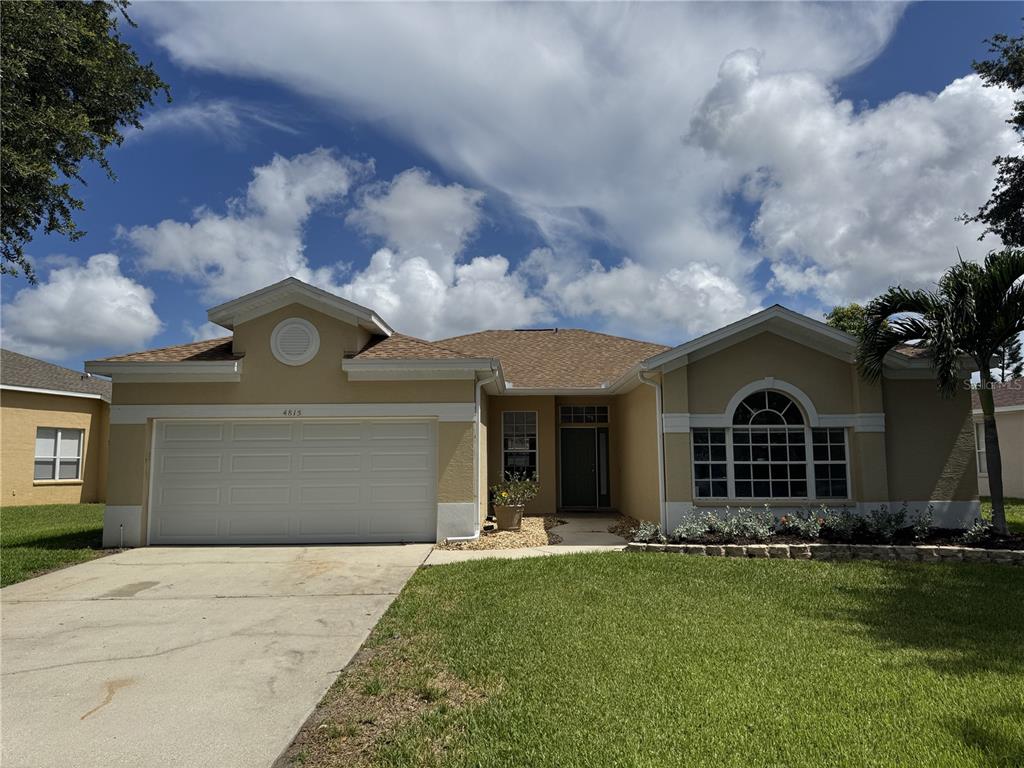 A single-story house with a two-car garage, tan stucco exterior, and a large arched window — 4815 50TH AVENUE W, BRADENTON, FL