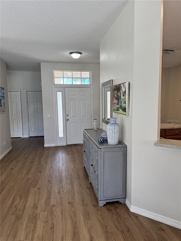 An entryway features light wood-look flooring, a white front door, and a gray console table — 4815 50TH AVENUE W, BRADENTON, FL