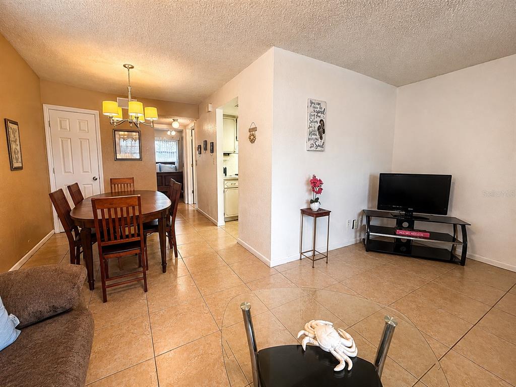 A dining area with a wooden table and chairs sits adjacent to a living room — 6044 22ND AVENUE N UNIT 2, ST PETERSBURG, FL