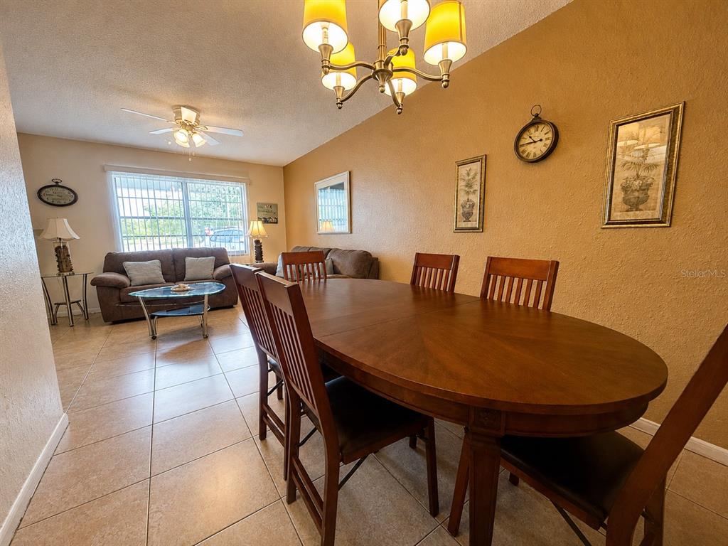 A dining area with a wooden table and chairs sits adjacent to a living room — 6044 22ND AVENUE N UNIT 2, ST PETERSBURG, FL