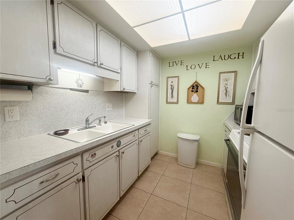 A kitchen features white cabinets, a double-basin sink, light countertops, and a tiled floor — 6044 22ND AVENUE N UNIT 2, ST PETERSBURG, FL