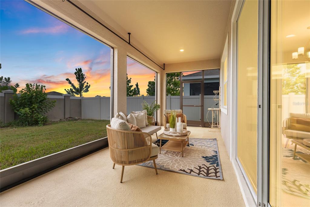 A covered patio with outdoor furniture, a patterned rug, and a view of a fenced yard — 8136 WHEAT STONE DRIVE, ZEPHYRHILLS, FL