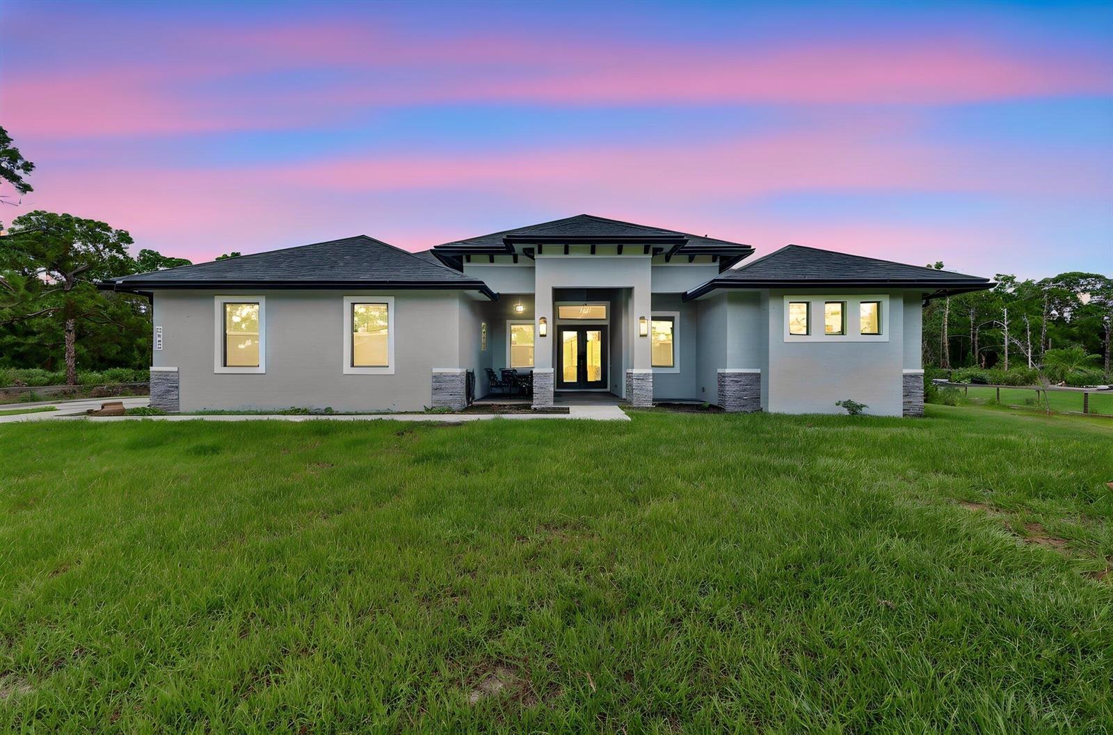 A single-story house with a gray exterior, stone accents, and a dark roof at dusk — 2643 Dyer Road, Fort Pierce FL 34952, FORT PIERCE, FL
