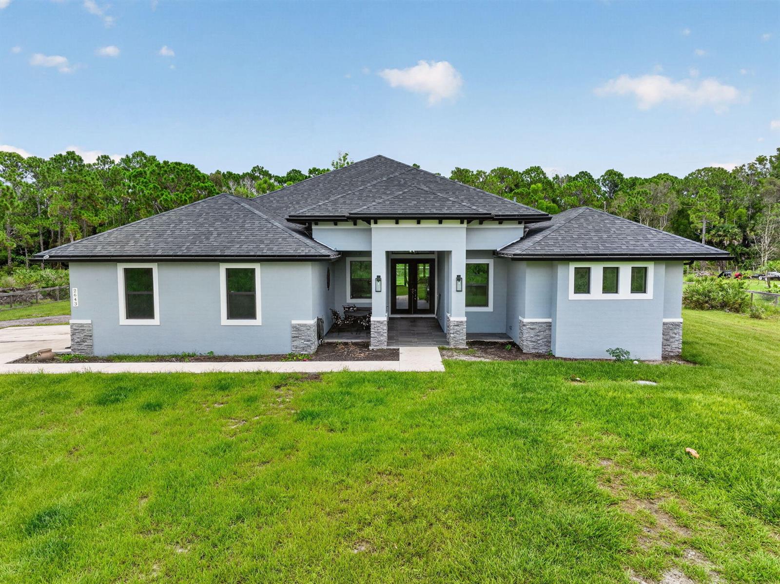 A single-story house with a gray stucco exterior, stone accents, and a dark shingled roof — 2643 Dyer Road, Fort Pierce FL 34952, FORT PIERCE, FL