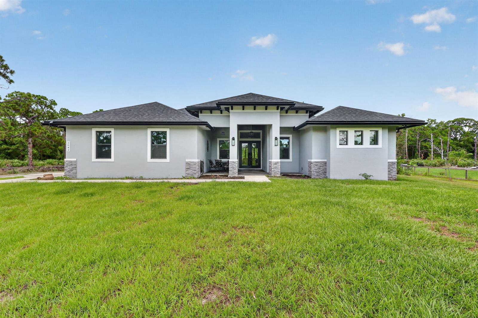 A single-story house with a gray stucco exterior, stone accents, and a dark shingled roof — 2643 Dyer Road, Fort Pierce FL 34952, FORT PIERCE, FL