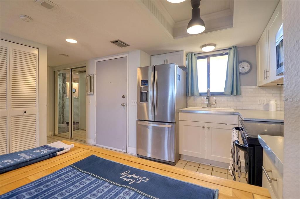 A kitchen features white cabinets, stainless steel appliances, a subway tile backsplash, and a wooden island — 5915 SEA RANCH DRIVE UNIT 211, HUDSON, FL