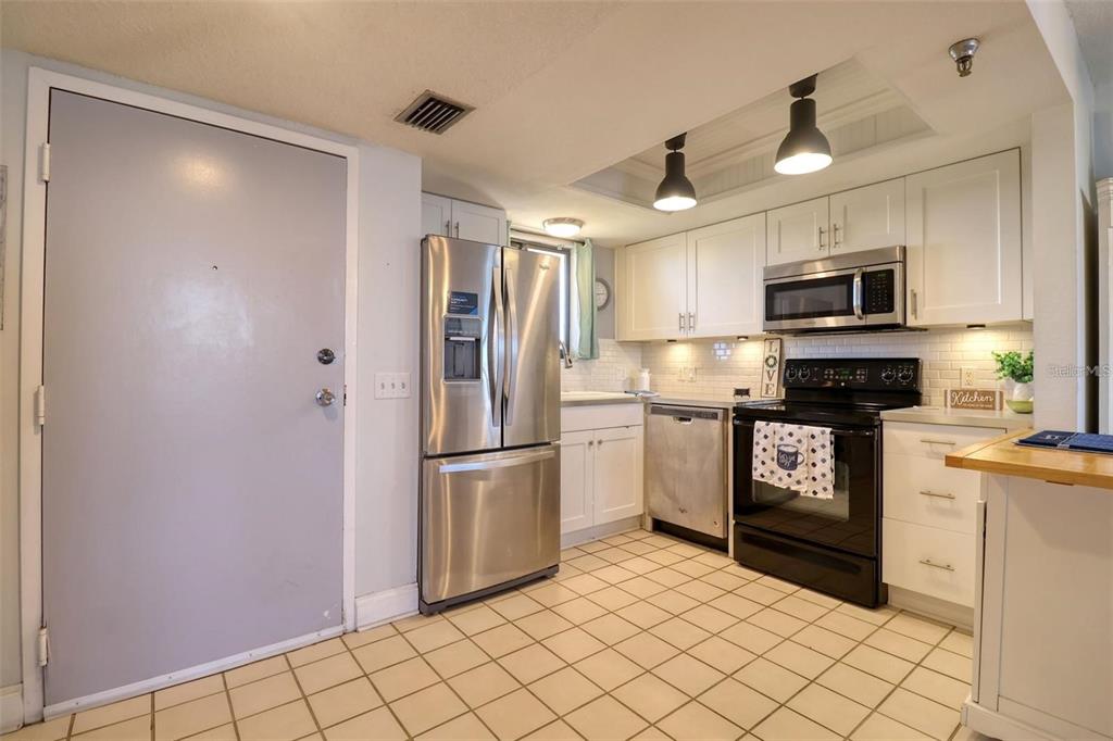 A kitchen features white cabinets, stainless steel appliances, a black stove, and tiled flooring — 5915 SEA RANCH DRIVE UNIT 211, HUDSON, FL