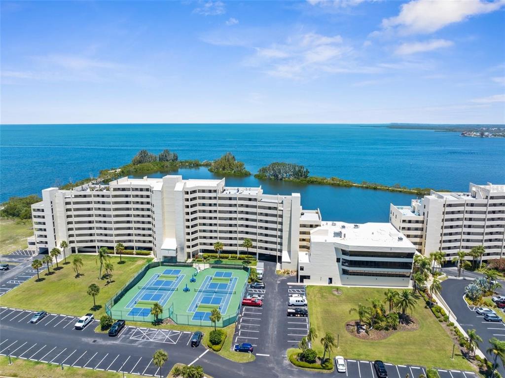An aerial view shows a large apartment complex with tennis courts and a waterfront location — 5915 SEA RANCH DRIVE UNIT 211, HUDSON, FL