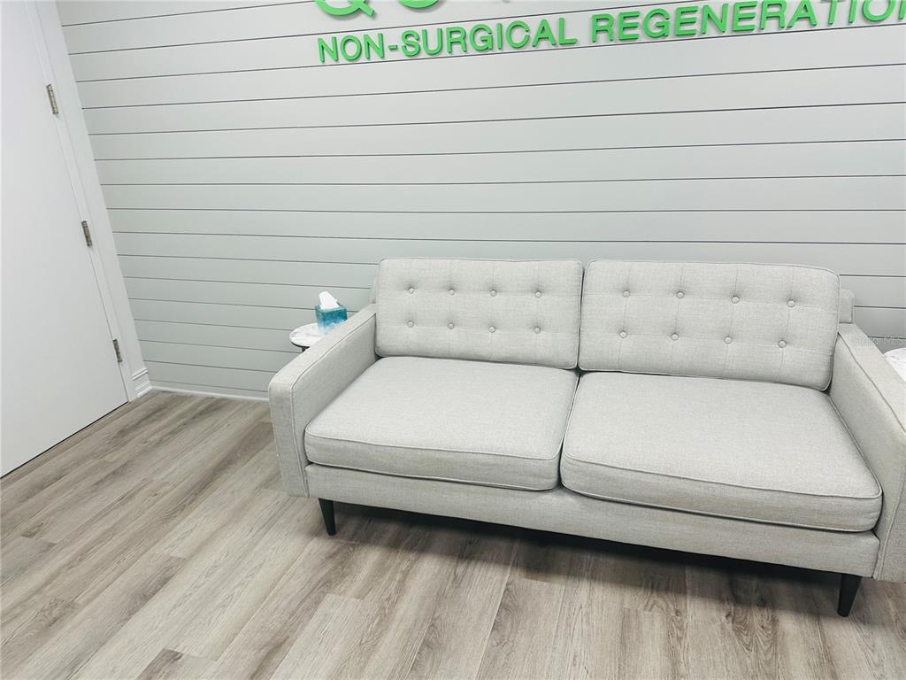 A light gray sofa sits against a shiplap wall in a room with wood flooring — 4106 W LAKE MARY BOULEVARD UNIT 205, LAKE MARY, FL