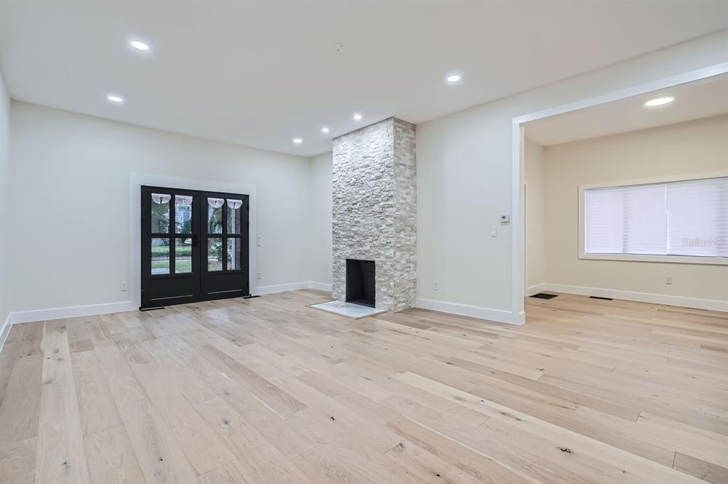 A living room features light wood flooring, a stone fireplace, and black French doors — 734 S MILLS AVENUE, ORLANDO, FL