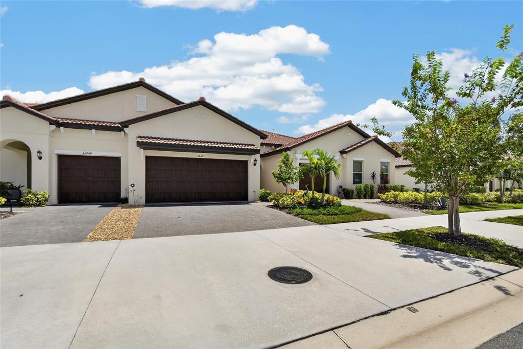 A view of the exterior of a suburban house with two garage doors and landscaping — 17242 HOLLY WELL AVENUE, WIMAUMA, FL