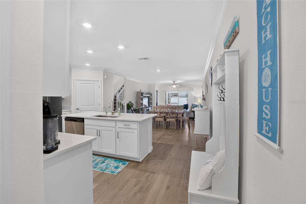 A kitchen with white cabinets and an island overlooks a dining area and living space — 17242 HOLLY WELL AVENUE, WIMAUMA, FL