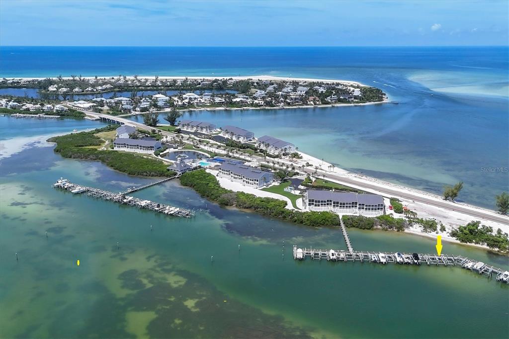 An aerial view shows a coastal resort with multiple buildings, a long boat dock, and surrounding water — 6040 BOCA GRANDE CAUSEWAY UNIT 11 Boat Slip, BOCA GRANDE, FL