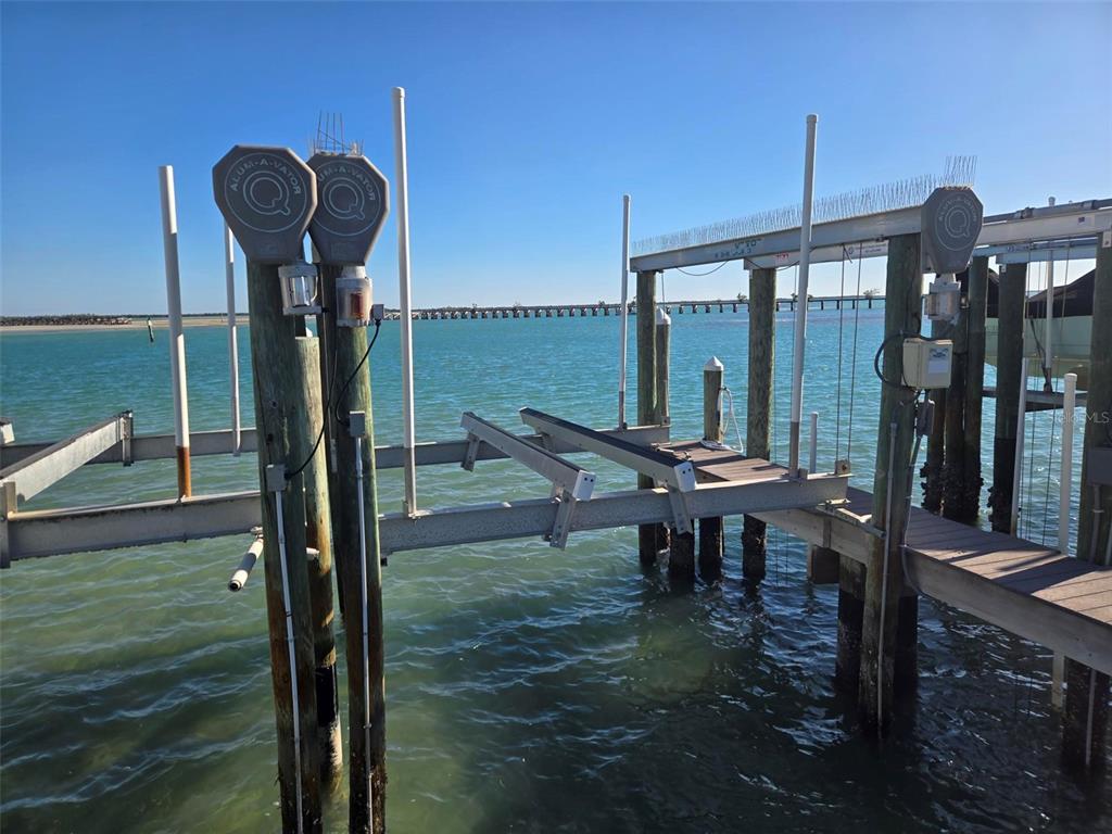 A boat lift with metal framing and pilings sits over calm water under a clear sky — 6040 BOCA GRANDE CAUSEWAY UNIT 11 Boat Slip, BOCA GRANDE, FL
