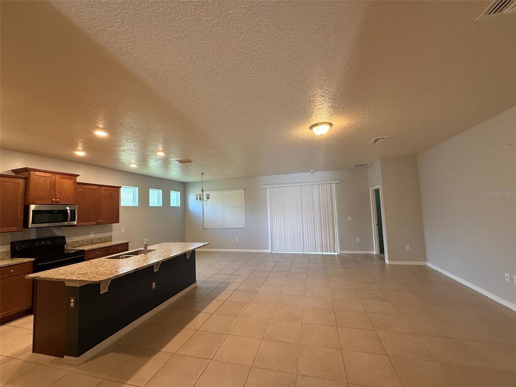 An open-concept kitchen with granite countertops and tile flooring flows into a spacious living area — 12374 EASTPOINTE DRIVE, DADE CITY, FL