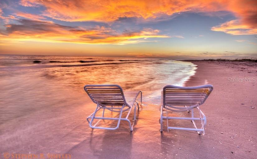 Two white lounge chairs sit on a sandy beach at sunset near the ocean water — 177 GULF BOULEVARD UNIT A, PLACIDA, FL