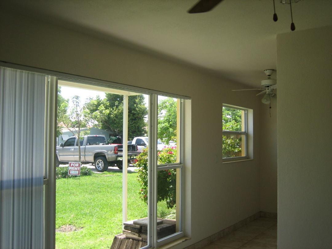 An interior view of a sunroom with tile flooring, a ceiling fan, and large windows — 231 NE 24th Avenue # 1, Pompano Beach FL 33064, POMPANO BEACH, FL