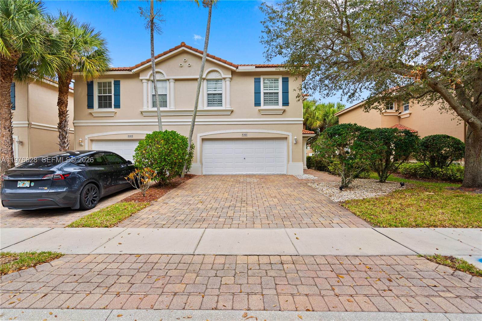 A two-story townhouse features a paved driveway, a two-car garage, and blue window shutters — 4301 Macarthur Palm Trl, Green Acres FL 33463, GREEN ACRES, FL
