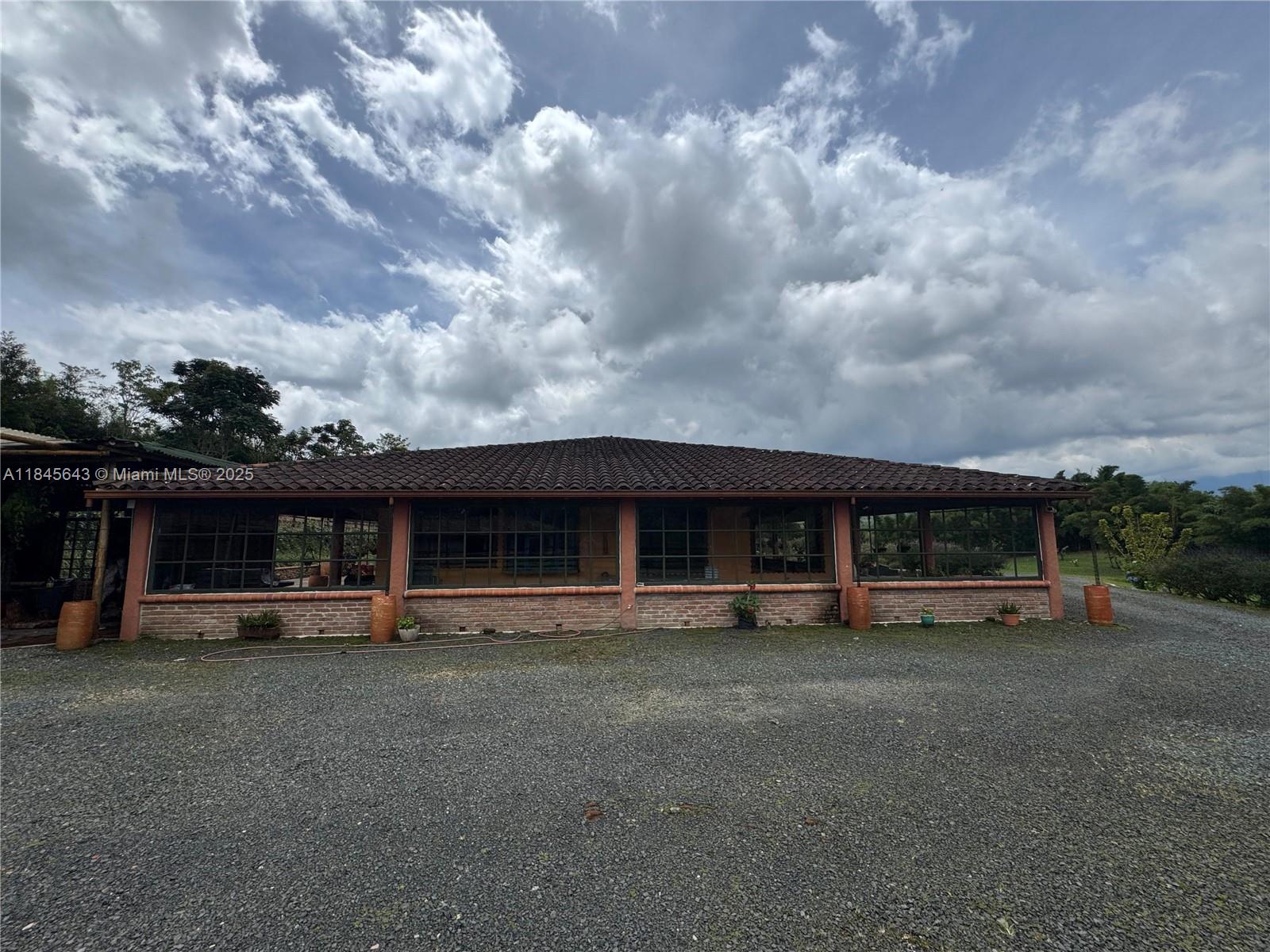 A single-story house with a tiled roof and large windows sits on a gravel lot — 2222 via Filandia/Armenia, NA, NA