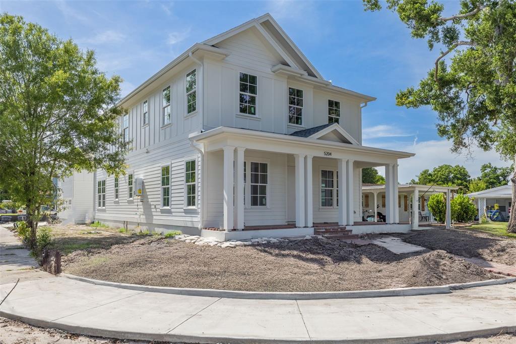 A white two-story house features a covered front porch with columns and brick steps — 5204 10TH STREET N, ST PETERSBURG, FL