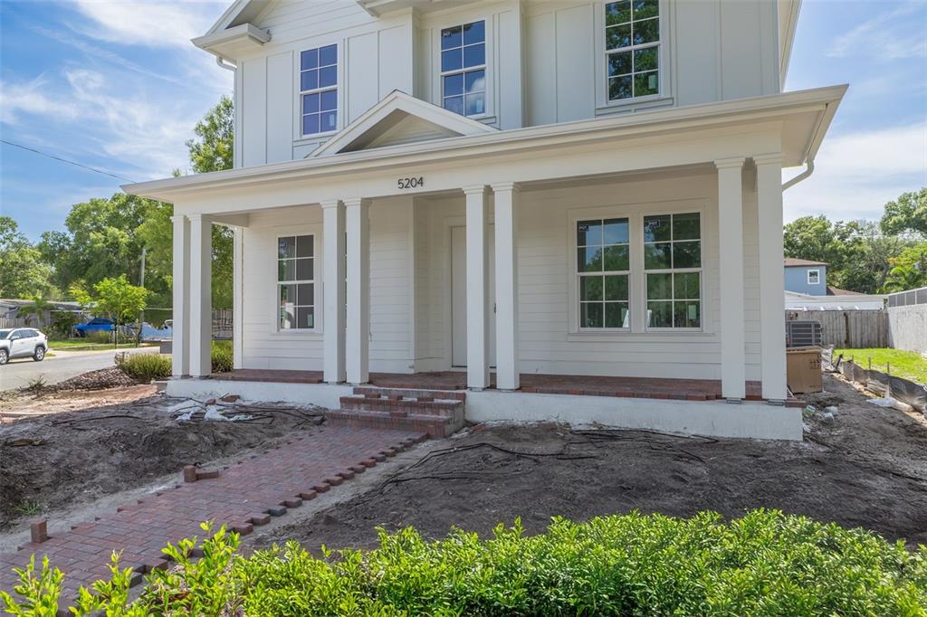 A white two-story house features a brick patio and walkway between two building sections — 5204 10TH STREET N, ST PETERSBURG, FL