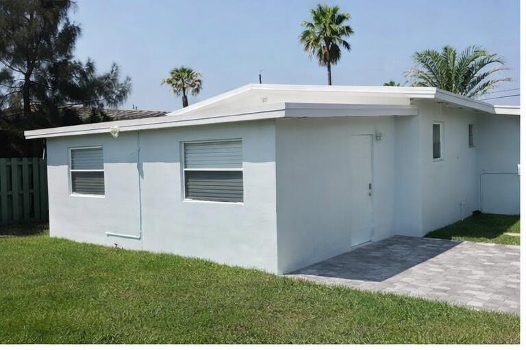 A white exterior wall of a house features two windows, a door, and a paver patio — 621 NE 3rd Avenue, Delray Beach FL 33444, DELRAY BEACH, FL