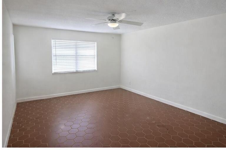An empty bedroom features white walls, a ceiling fan, and brown hexagonal floor tiles — 621 NE 3rd Avenue, Delray Beach FL 33444, DELRAY BEACH, FL