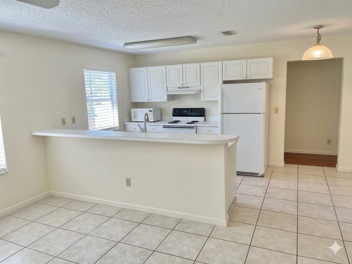 A kitchen with white cabinets, white appliances, and a breakfast bar over tile flooring — 621 NE 3rd Avenue, Delray Beach FL 33444, DELRAY BEACH, FL