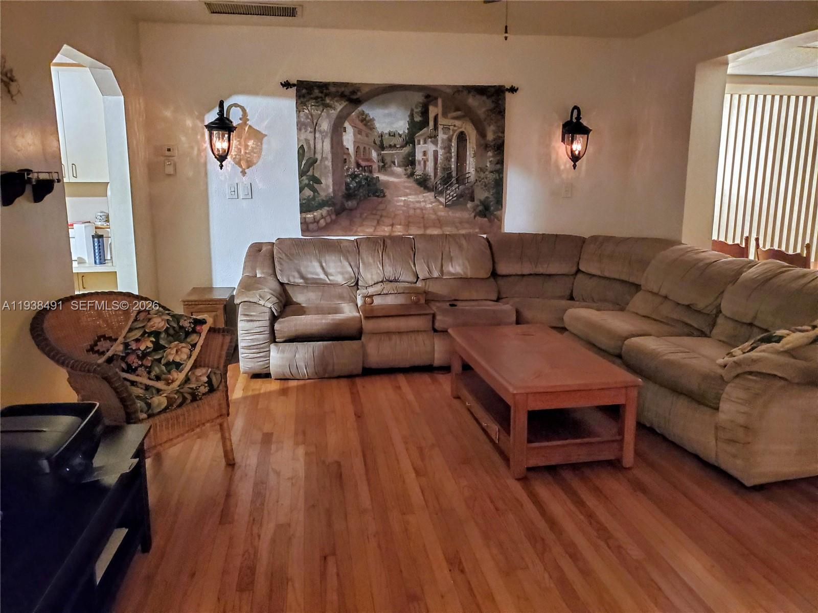 A living room features a large sectional sofa, a wooden coffee table, and wall sconces — 1846 Wiley St, Hollywood FL 33020, HOLLYWOOD, FL