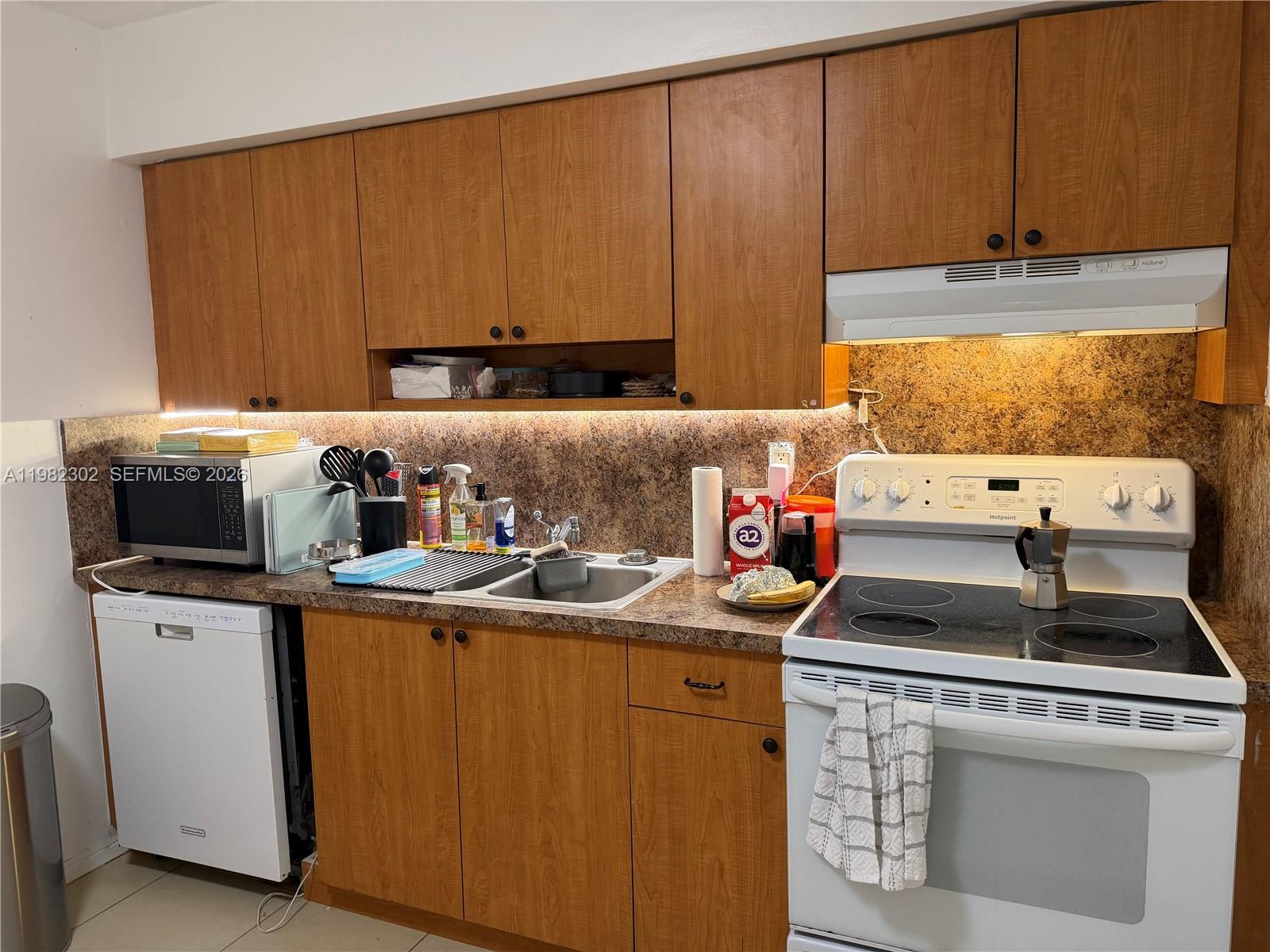 A kitchen features wood cabinets, a white stove, a dishwasher, and a speckled countertop — 2620 SW 51st St # 2, Dania Beach FL 33312, DANIA BEACH, FL