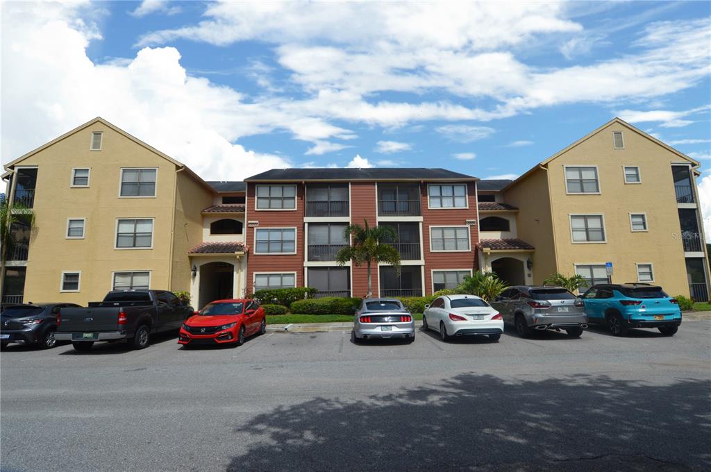 A three-story apartment building with a parking lot in front and several parked cars — 11901 4TH STREET N UNIT 10206, ST PETERSBURG, FL