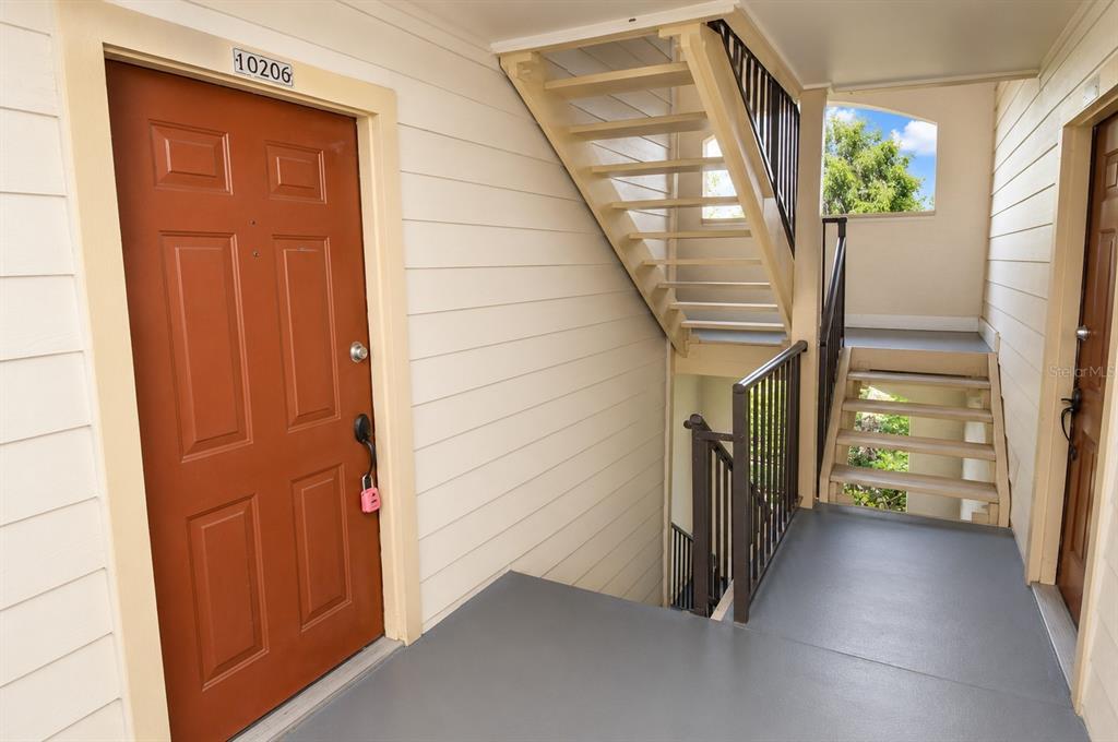 An exterior view of an apartment building landing with stairs and two unit doors — 11901 4TH STREET N UNIT 10206, ST PETERSBURG, FL