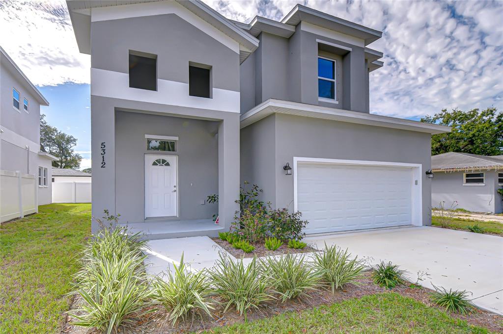 A two-story gray house features a white garage door and a front entrance walkway — 5312 76TH AVENUE N, PINELLAS PARK, FL