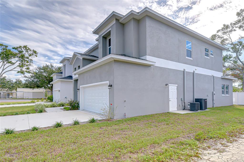 A side view of a two-story gray stucco house with a white garage door — 5312 76TH AVENUE N, PINELLAS PARK, FL