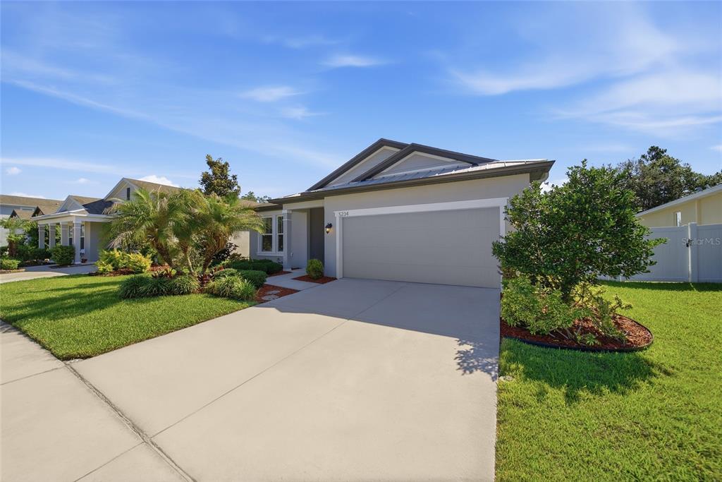 A single-story suburban house with a two-car garage, concrete driveway, and landscaped front yard — 5234 TURTLE BAY DRIVE, WESLEY CHAPEL, FL